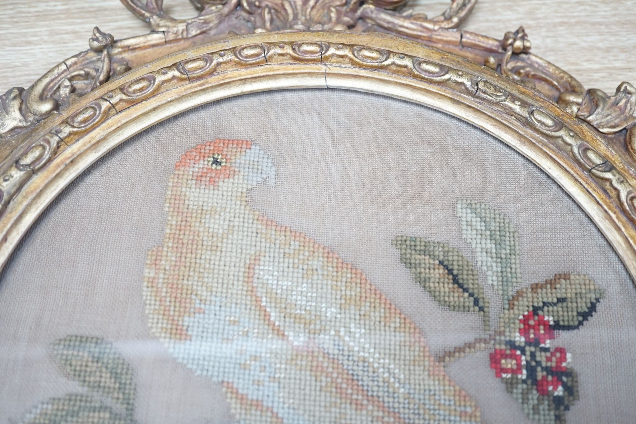 A pair of 19th century giltwood framed circular needleworks of parrots, 26cm diameter excl frame